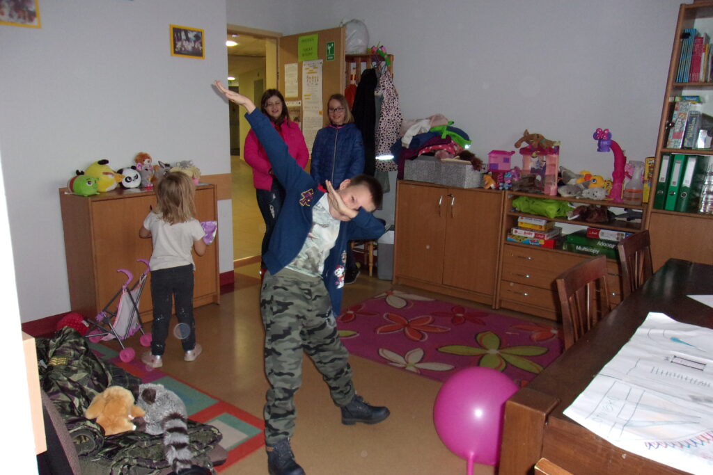 Dwie młode kobiety obserwują zabawę ruchową dzieci w pokoju pełnym zabawek